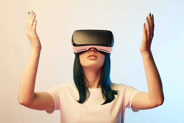 Attractive young woman gesturing while wearing virtual reality headset on beige and blue — Stock Photo