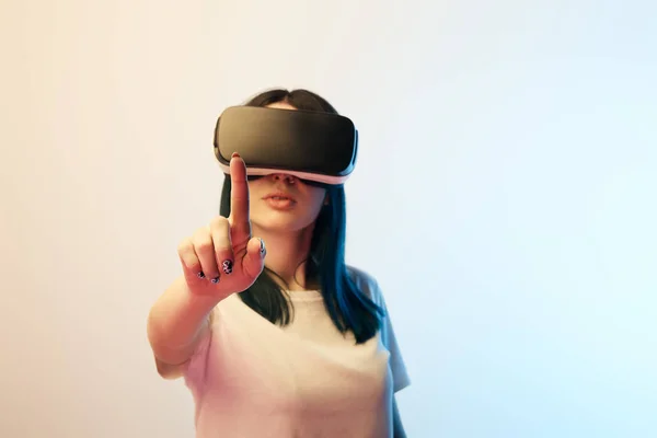 Selective focus of girl pointing with finger while wearing virtual reality headset on beige and blue — Stock Photo
