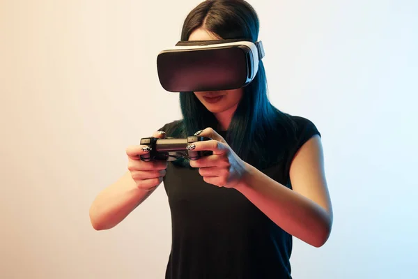 KYIV, UCRANIA - 5 DE ABRIL DE 2019: Mujer joven jugando a videojuegos con auriculares de realidad virtual en beige y azul - foto de stock