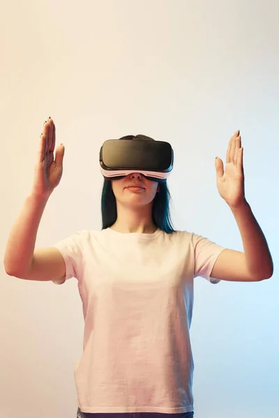 Brunette young woman in virtual reality headset gesturing on beige and blue — Stock Photo