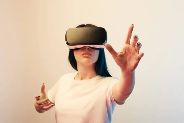 Morena mujer joven en realidad virtual auriculares gestos en beige - foto de stock