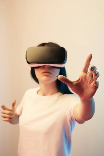Selective focus of brunette young woman in virtual reality headset gesturing on beige — Stock Photo