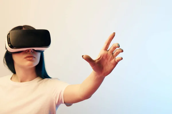 Selective focus of young woman in virtual reality headset gesturing on beige and blue — Stock Photo