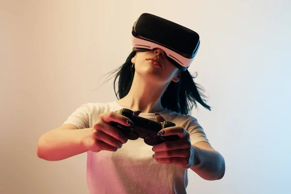 KYIV, UKRAINE - APRIL 5, 2019: Selective focus of woman in white t-shirt wearing virtual reality headset and holding joystick on beige and blue — Stock Photo