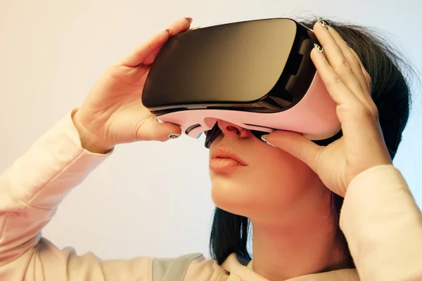 Primo piano di bella donna bruna toccare auricolare realtà virtuale su beige e blu — Foto stock