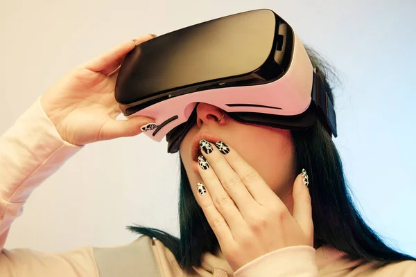 Vista a basso angolo di donna sorpresa che copre la bocca mentre indossa auricolare realtà virtuale su beige e blu — Foto stock