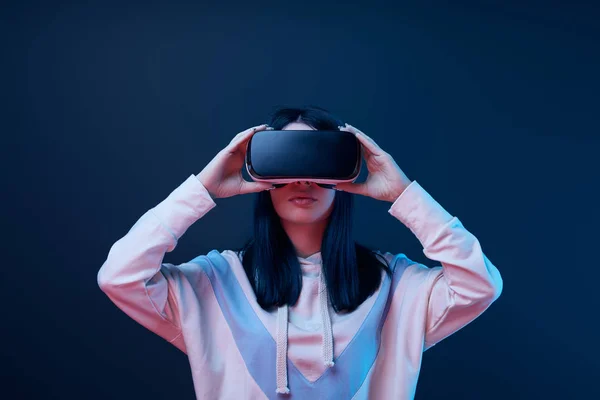 Brunette young woman touching virtual reality headset on blue — Stock Photo