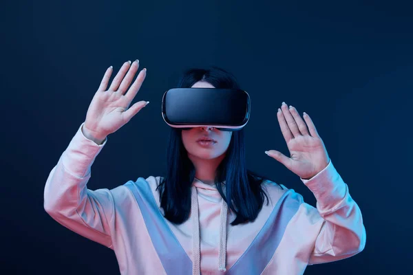 Young brunette woman wearing virtual reality headset and gesturing on blue — Stock Photo