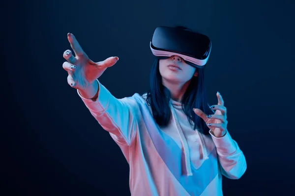 Selective focus of young woman wearing virtual reality headset and gesturing on blue — Stock Photo