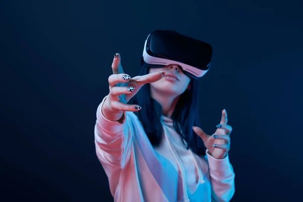 Selective focus of girl wearing virtual reality headset and gesturing on blue — Stock Photo