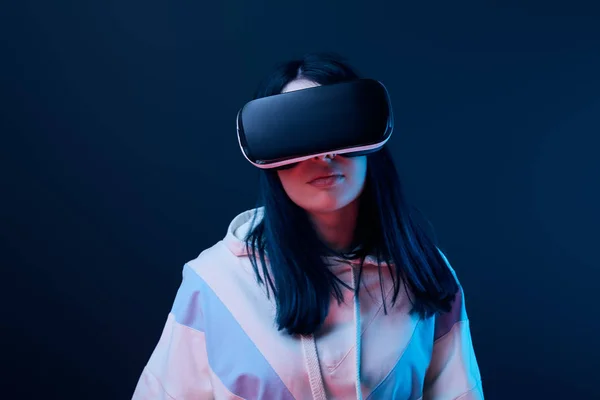 Morena joven usando auriculares de realidad virtual en azul - foto de stock