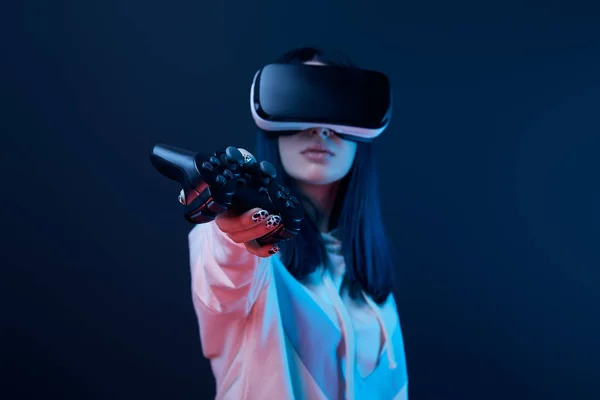 KYIV, UKRAINE - APRIL 5, 2019: Selective focus of young woman holding joystick while using virtual reality headset on blue — Stock Photo