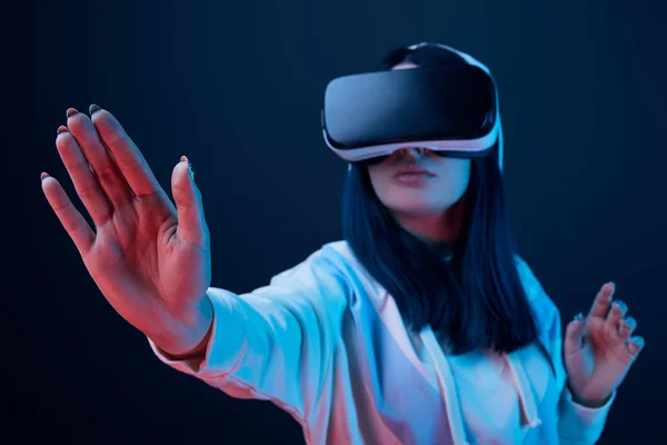Foco seletivo de gestos menina ao usar fone de ouvido realidade virtual em azul — Fotografia de Stock