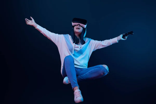 KYIV, UCRÂNIA - 5 de abril de 2019: Mulher feliz em realidade virtual headset levitando e segurando joystick em azul — Fotografia de Stock