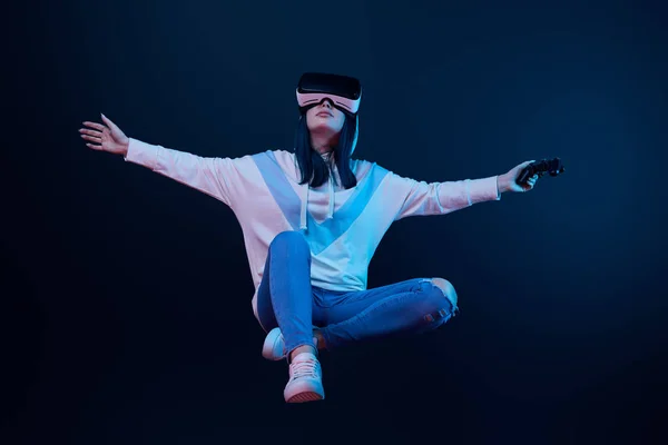 QUIIV, UCRÂNIA - ABRIL 5, 2019: Jovem mulher em realidade virtual headset levitando e segurando joystick em azul — Fotografia de Stock