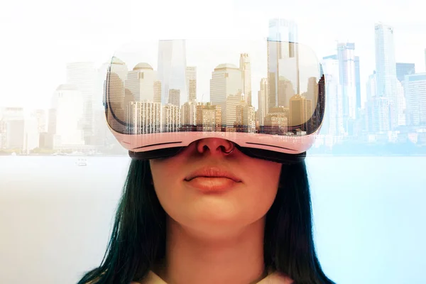 Doble exposición de chica morena con auriculares de realidad virtual y ciudad moderna con rascacielos - foto de stock