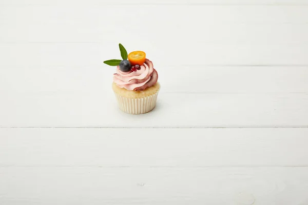 Cupcake with grape, garnet and kumquat on white surface — Stock Photo