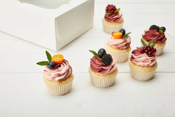 Cupcake con bacche e panna su superficie bianca — Foto stock