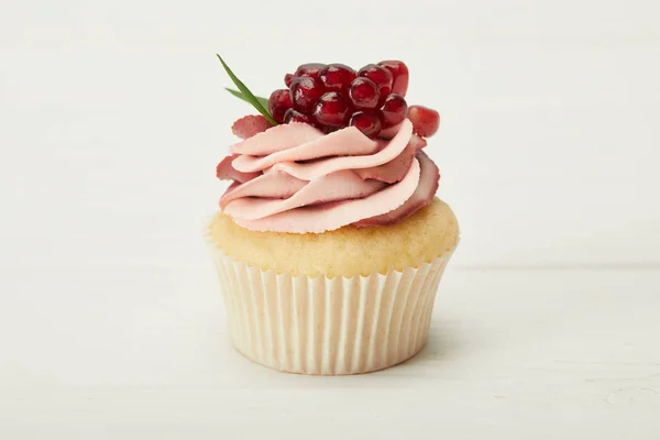 Cupcake saboroso com creme e granada na superfície branca — Fotografia de Stock
