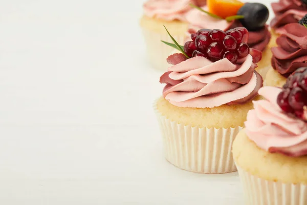 Selective focus of cupcakes with cream and berries on white surface — Stock Photo