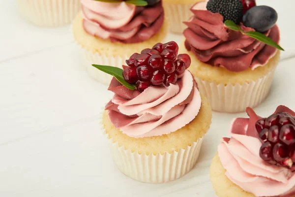 Foyer sélectif de cupcakes avec crème et baies sur la surface blanche — Photo de stock