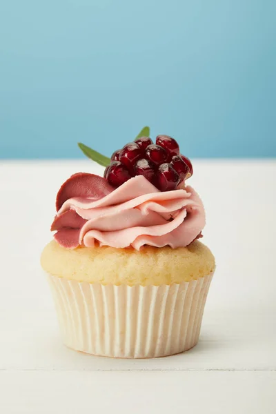 Gustoso cupcake con crema su superficie bianca isolata su blu — Foto stock