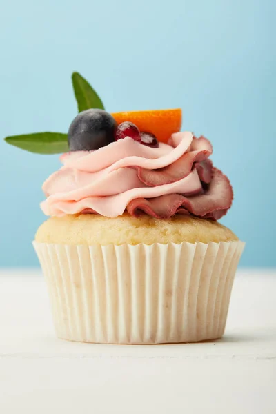 Gustoso cupcake con crema su superficie bianca isolata su blu — Foto stock