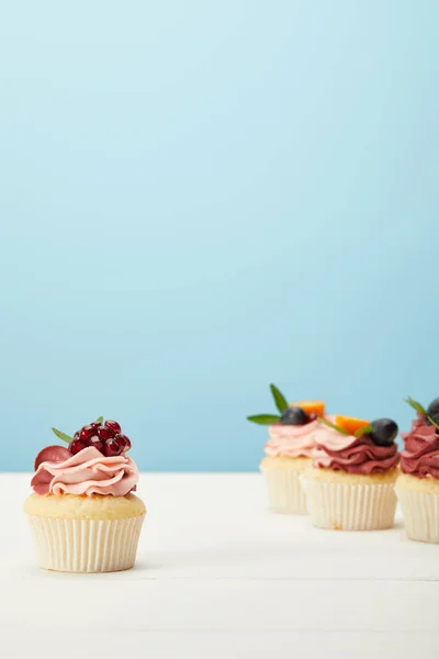 Enfoque selectivo de cupcakes en la superficie blanca aislado en azul - foto de stock
