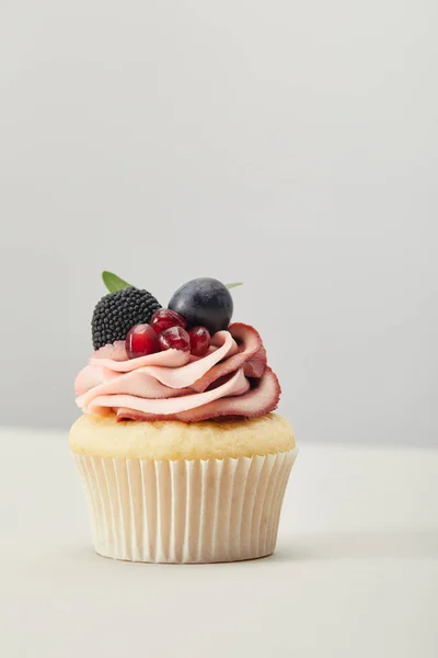 Cupcake with grape, garnet and blackberry isolated on grey — Stock Photo