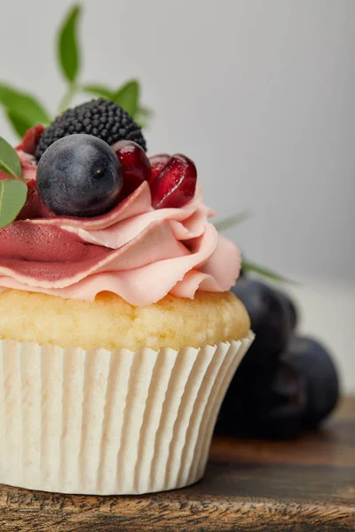 Cupcake doce saboroso com bagas na placa de corte de madeira — Fotografia de Stock