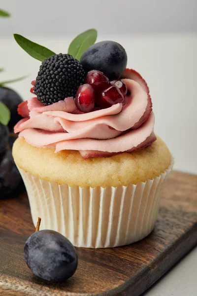 Tasty sweet cupcake with berries on wooden cutting board — Stock Photo