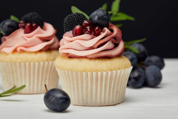 Cupcakes com bagas na superfície branca isolada em preto — Fotografia de Stock