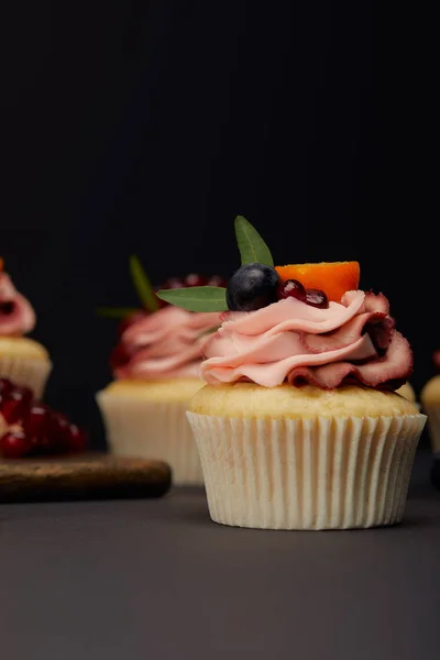 Cupcake con frutti e bacche su superficie grigia isolati su nero — Foto stock