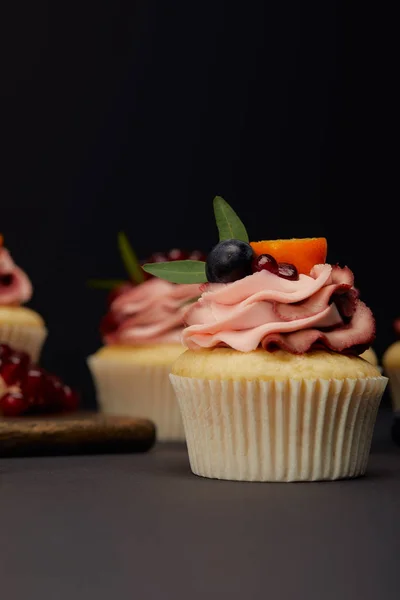 Magdalenas con frutas y bayas sobre una superficie gris aislada sobre negro - foto de stock