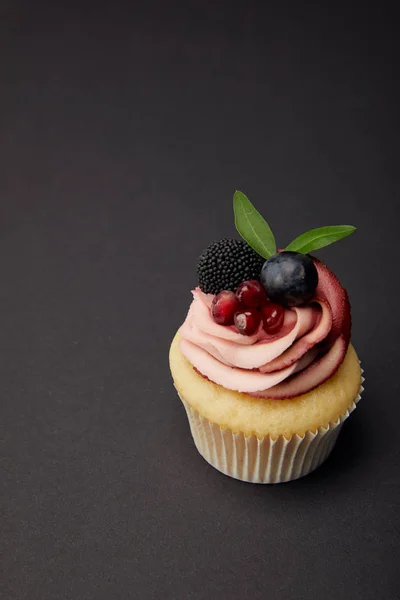Cupcake with garnet, blackberry and grape on black surface — Stock Photo