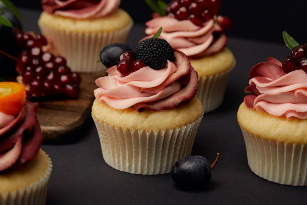 Cupcakes with fruits and berries on black surface — Stock Photo