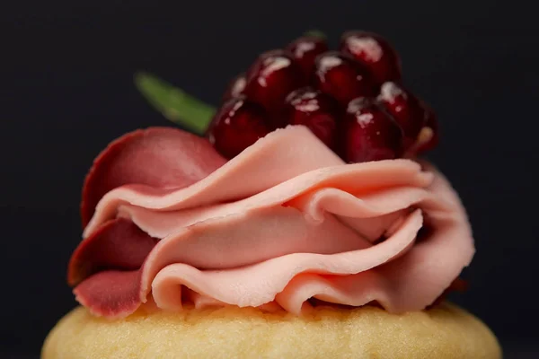 Close up view of cupcake with cream and garnet isolated on black — Stock Photo