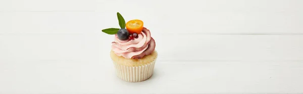 Panoramic shot of cupcake with kumquat, garnet and grape on white surface — Stock Photo