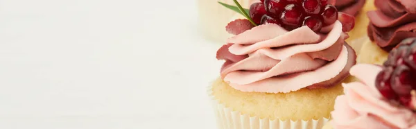 Panoramic shot of cupcakes with cream and garnet isolated on white — Stock Photo