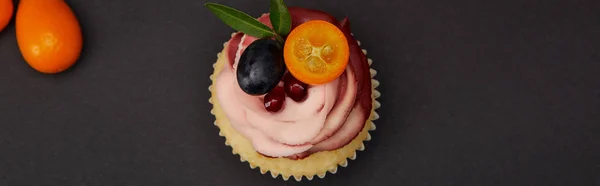 Tiro panorâmico de cupcake com creme e frutas na superfície preta — Fotografia de Stock