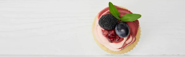 Панорамный снимок кекса со сливками, гранатом и ягодами на белой поверхности — стоковое фото