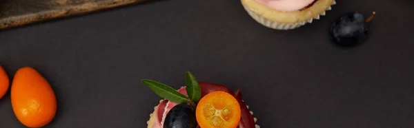Plano panorámico de cupcakes con kumquats en la superficie negra - foto de stock