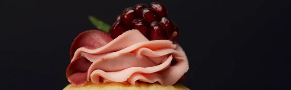 Panoramic shot of cupcake with cream and garnet isolated on black — Stock Photo