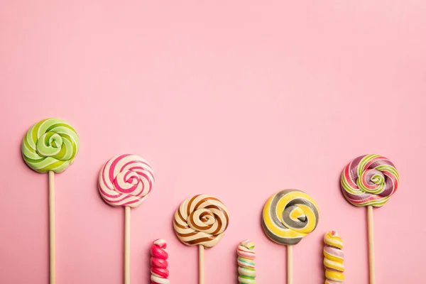 Top view of delicious swirl lollipops on wooden sticks on pink background with copy space — Stock Photo