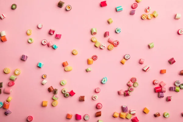 Vue de dessus de délicieux bonbons multicolores dispersés sur fond rose — Photo de stock