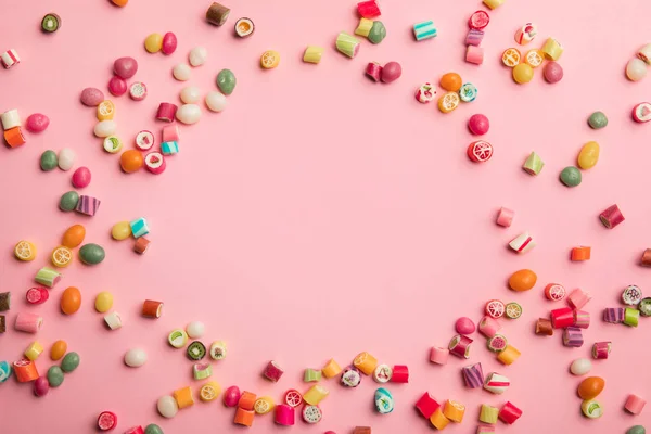 Вид зверху різнокольорових цукерок, розкиданих на рожевому фоні з копією простору — стокове фото