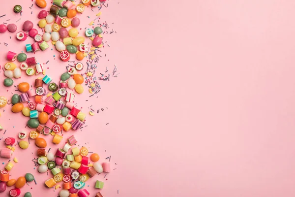 Draufsicht auf bunte Bonbons und Streusel auf rosa Hintergrund mit Kopierraum verstreut — Stock Photo