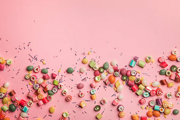 Vista superior de coloridos caramelos sabrosos y salpicaduras esparcidas sobre fondo rosa con espacio de copia - foto de stock