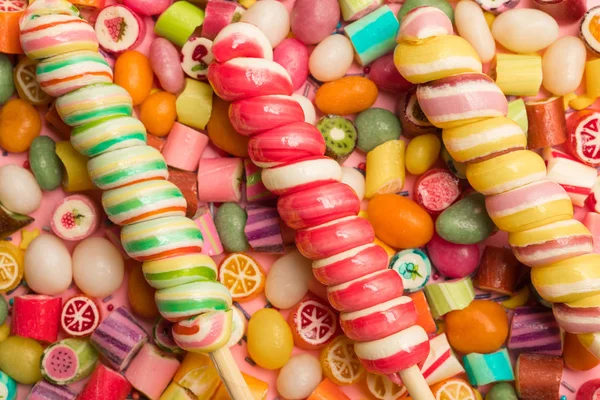 Vue de dessus de délicieux bonbons au caramel multicolores et sucette tourbillonnante sur bâtons de bois — Photo de stock