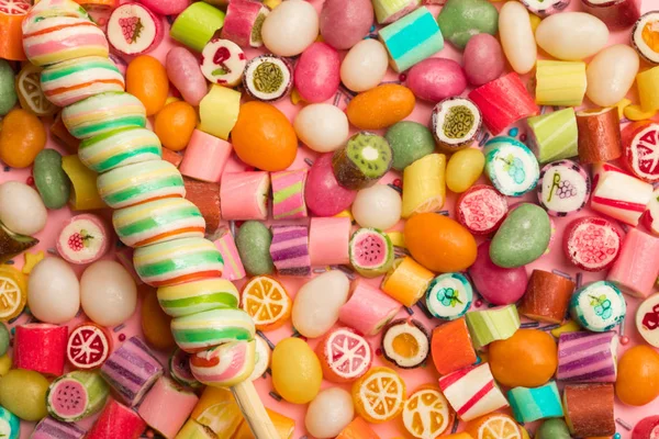 Top view of bright delicious multicolored caramel candies and swirl lollipop on wooden stick — Stock Photo